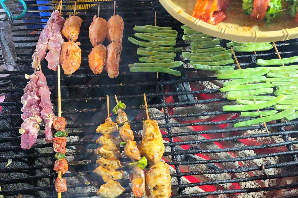 Skewers and vegetables grilling over charcoal at a street stall in Sapa