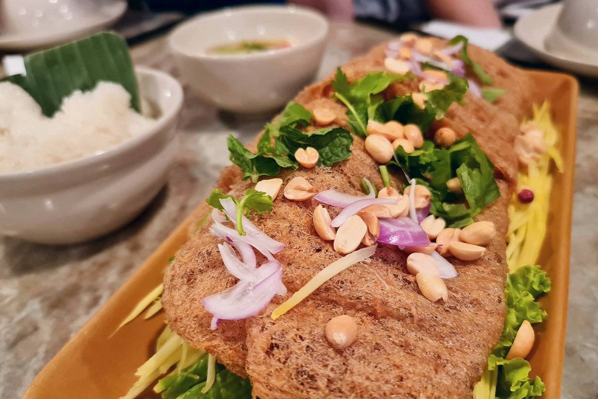 A Vietnamese dish topped with herbs and peanuts, served on a wooden board