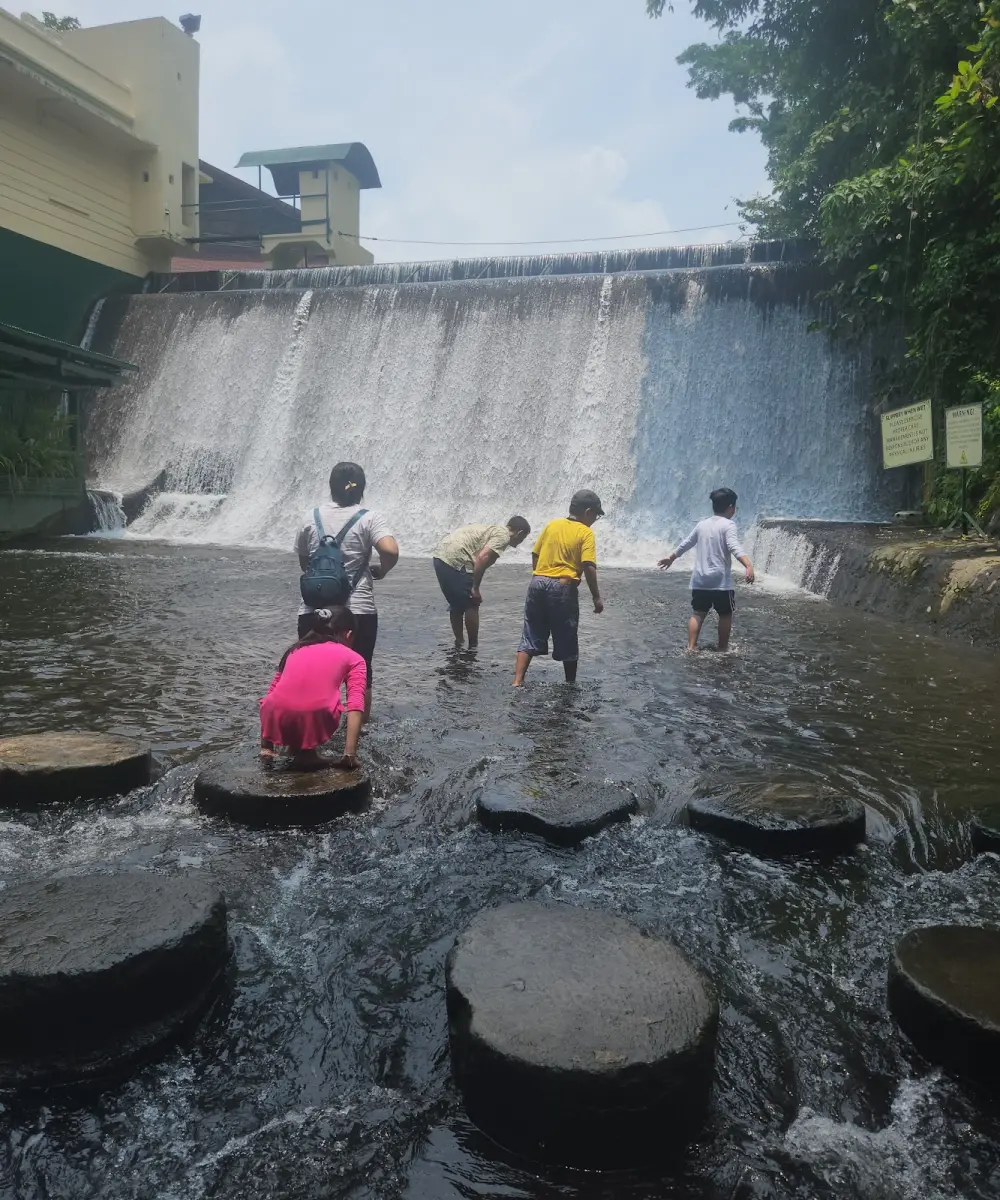 Khách lội nước qua các bậc đá dưới thác Villa Escudero